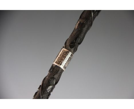 An Irish carved bog oak walking cane, decorated with shamrock, a harp and a serpent, with three silver mounts, one inscribed 