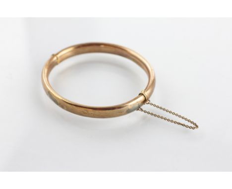 A 9ct yellow gold hinged bangle, the hollow bangle of plain form and with attached safety chain, weight 10.5gms  