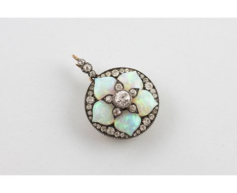 An opal and diamond set brooch/pendant circa 1910, the circular pendant in flower head design, set with a central old brillia