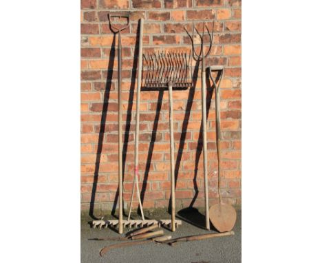 An assortment of vintage gardening and farm tools, including a rake, three prong tool, wire tighteners, peat shovel etc
