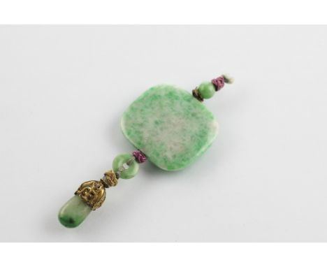 A Chinese jade pendant, the central cushion shaped jade panel suspending a two bead drop with gilt metal caps, 9cm long 