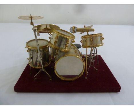 A scale model of a drum kit mounted on a rectangular plinth