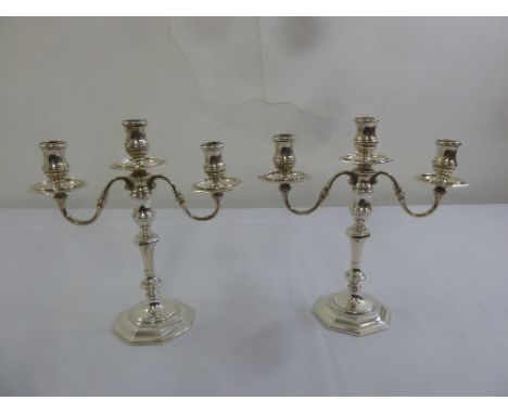 A pair of silver 18th century style three light candelabra on raised octagonal bases, London 1965