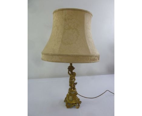 A gilt metal table lamp with putti figurines, to include silk shade