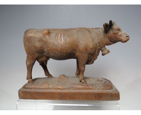 A BLACK FOREST WOOD CARVING OF A COW, with a large cowbell around its neck, on a naturalistic base, W 22 cm  together with A 