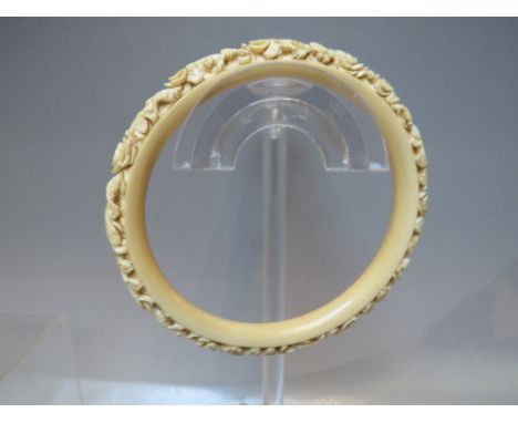 AN ANTIQUE CARVED IVORY BANGLE, internal Dia. 8.1 cm