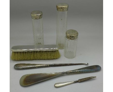 Three silver topped jars, silver backed brush, silver handled shoe horn and button hook