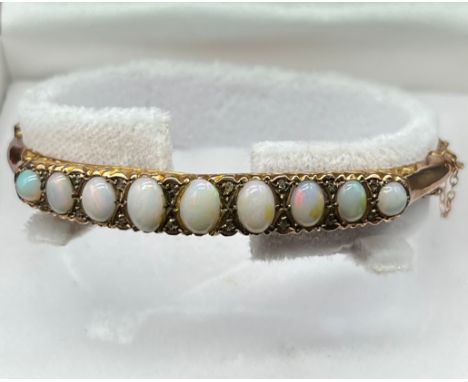 9ct yellow gold bangle fitted with 9 varying sized opals and small diamond chips [6.62x4.68mm- large central opal] [6.40grams