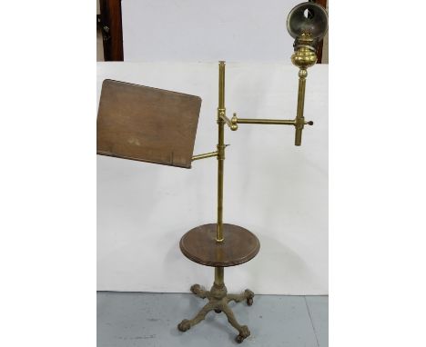 19thC Brass Adjustable Lectern, with attached oil lamp and a circular mahogany shelf and cast iron claw feet  the base, casrs