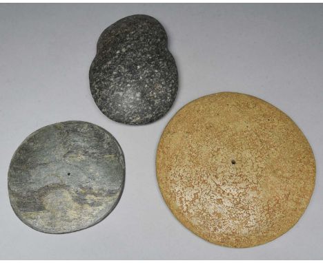 A stone axe head8.5cm long,and two stone discs, each with a drilled hole to the centre, 22cm and 17cm diameter. (3)