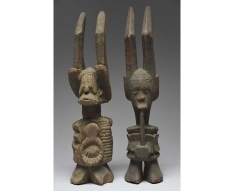 Two Ibo Ikenga figuresNigeriaone with a pipe and the other with associated charms,37.7cm and 36.6cm high. (2)