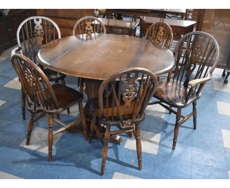 An Ercol Type Dark Oak Refectory Style Drop Leaf Dining Table with a Set of Six Matching Wheelback Chairs to include Two Carv