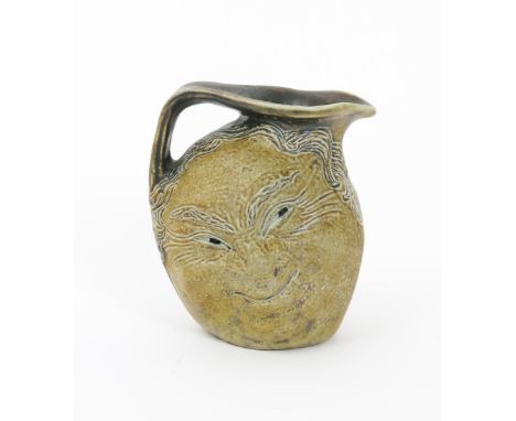 A Martin Brothers small face jug by Robert Wallace Martin, modelled to one side with a smiling face, the reverse with a pouti