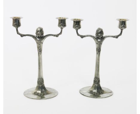 A pair of Continental pewter Secessionist twin-branch candlesticks,  eliptical bases rising up to twin branches, cast with an