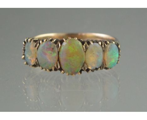 EDWARDIAN FIVE STONE OPAL RING set in yellow metal. The oval opals graduated from 8 x 5mm to 5.5 x 3mm. Ring size O.(B.P. 24%