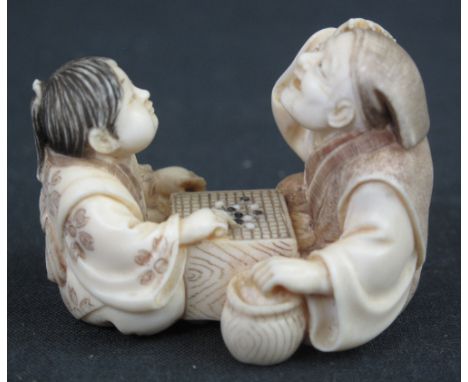 JAPANESE CARVED IVORY NETSUKE, father and son playing board game 'Go', signed to base: Yoshide, Taisho period, 5mm across app