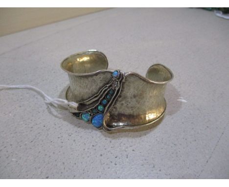 A silver coloured metal bangle set with opal coloured cabochons