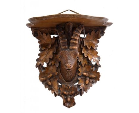 A SWISS CARVED LIMEWOOD WALL BRACKET WITH SERPENTINE SHELF SUPPORTED BY THE HEAD OF A MOUNTAIN GOAT WITH GLASS BEAD EYES ON A