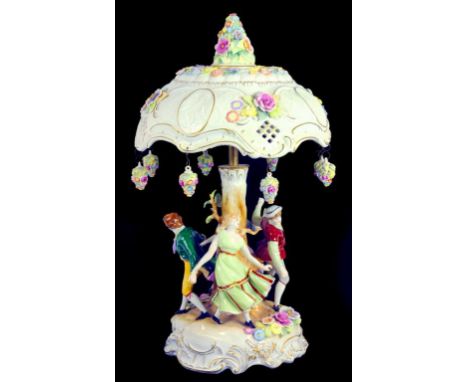 A CONTINENTAL PORCELAIN FLORAL ENCRUSTED LAMP, THE DOMED SHADE WITH LITHOPHANES, ON RUSTIC BASE SET WITH FOUR DANCERS, 57CM H