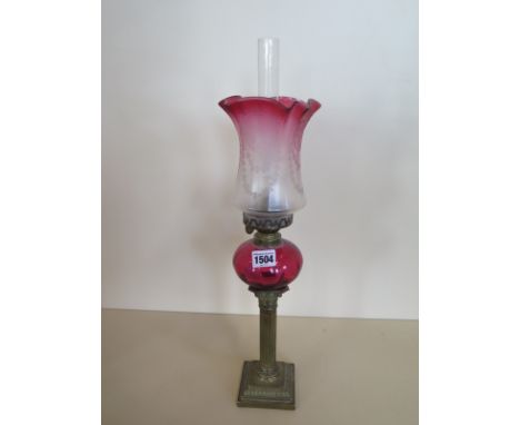 A pipe oil lamp with etched cranberry shade and cranberry reservoir, 51cm tall, small chip to shade , generally good conditio