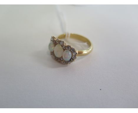 A three stone opal ring surrounded with small diamonds and an 18ct gold band, ring size Q, overall approx 5.5g 