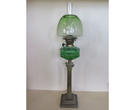 An oil lamp with a green tinted etched glass shade and green glass font, 81cm tall, small chips to glass, otherwise good 