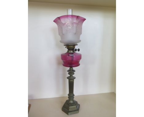 An oil lamp with an etched cranberry tinted shade and cranberry font, 81cm tall 