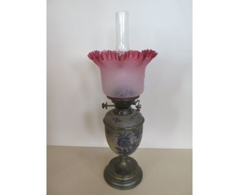 An oil lamp with ceramic body and glass font with cranberry tinted shade, 58cm tall, some usage wear but generally good, smal