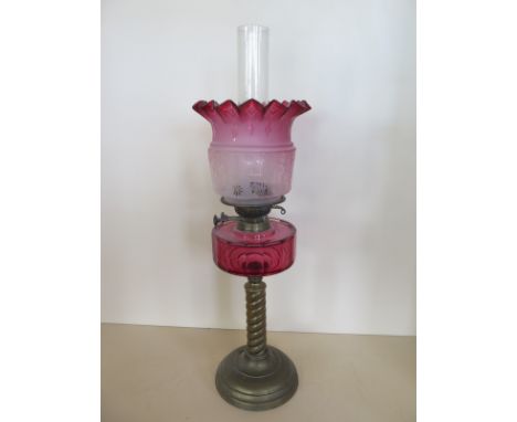 An oil lamp with cranberry font and tinted shade, 67cm tall, good condition, some wear to base 