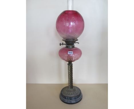 An oil lamp with cranberry glass font and cranberry globe shade, 73cm tall, minor chips to base of shade, otherwise good cond