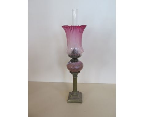A pipe oil lamp with cranberry etched shade and white and pink reservoir, 51cm tall, small chip to base of shade, otherwise g