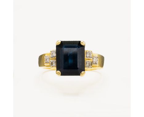 AN 18CT GOLD SAPPHIRE AND DIAMOND DRESS RING. the emerald cut sapphire claw set and flanked by diamond set shoulders, ring si