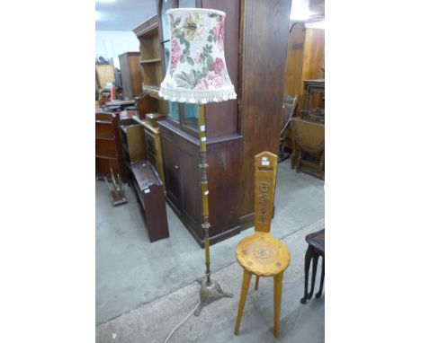 A carved oak spinning stool and a brass standard lamp 