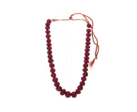 RUBY BEAD NECKLACE, formed by carved beads totalling approximately 950.00 carats, on an adjustable fabric necklace