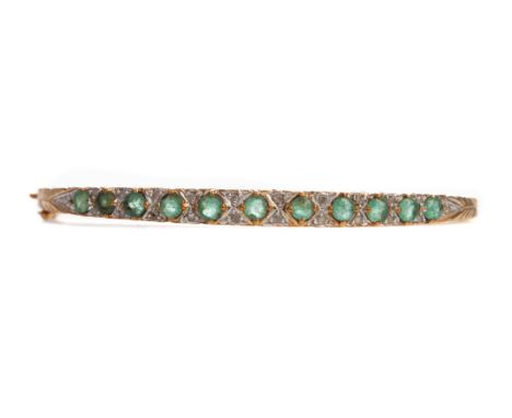 EMERALD AND DIAMOND BANGLE, the round emeralds interspaced by pairs of round brilliant cut diamonds totalling approximately 0