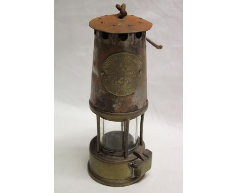 An old brass mounted steel miner's lamp by the Protector Lamp and Lighting Co.
