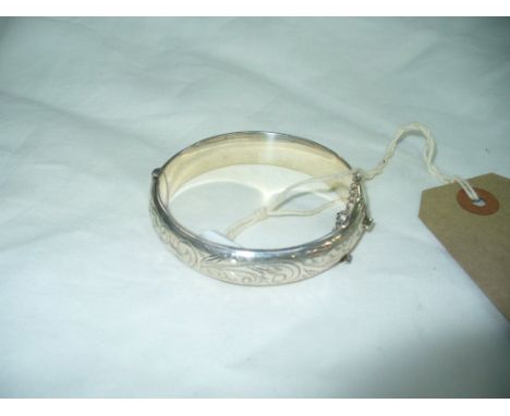 A Silver bangle with chased scrolling leaf decoration