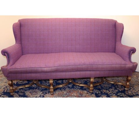 Queen Anne style sofa with wing back and outsplayed arms, on gilt angular S-scroll legs with bun feet joined by cross stretch