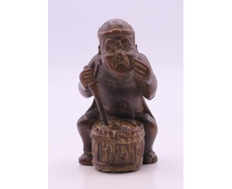 A netsuke formed as a man playing a drum. 5.5 cm high.