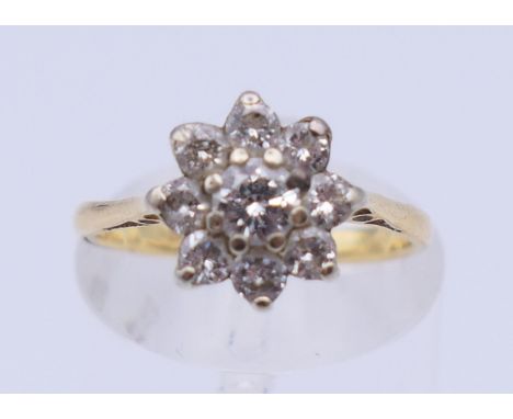 An 18 ct gold daisy cluster ring. Ring size J/K. 2.6 grammes total weight.