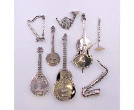 A collection of miniature silver instruments, including: harp, cello, flute, guitar, banjo, mandolin and French horn. Guitar 