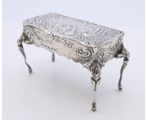 An embossed silver trinket box formed as a table, import marks for London 1899.  5 cm high, 8 cm wide, 4 cm deep. 67.9 gramme