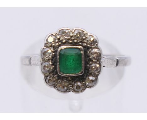 A platinum, diamond and emerald ring. Ring size N. 3.8 grammes total weight.