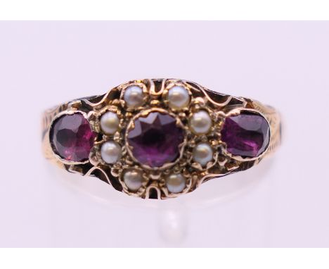 An antique 9 ct gold garnet and seed pearl ring. Ring size O. 1.9 grammes total weight.