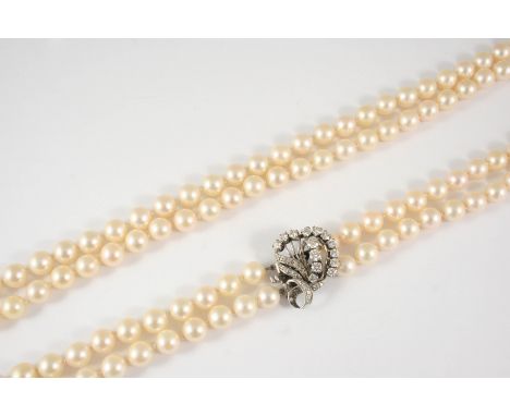 A TWO ROW UNIFORM CULTURED PEARL NECKLACE the pearls measure approximately 7.8mm., and are set to a diamond set foliate clasp