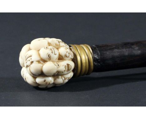 JAPANESE WALKING STICK, the ivory finial carved with numerous masks on an ebony shaft, length 85cm