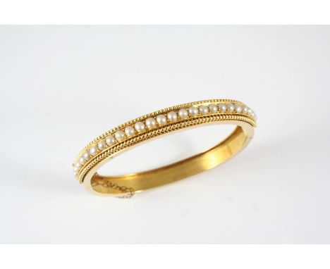 A VICTORIAN GOLD AND PEARL SET HALF HINGED BANGLE set to one side with a row of half pearls within a gold ball border, inner 