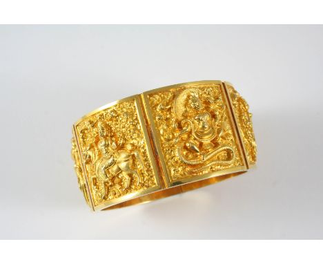 A INDIAN GOLD CARVED PANEL HINGED BANGLE formed with six gold panels, with engraved and embossed decoration depicting Indian 