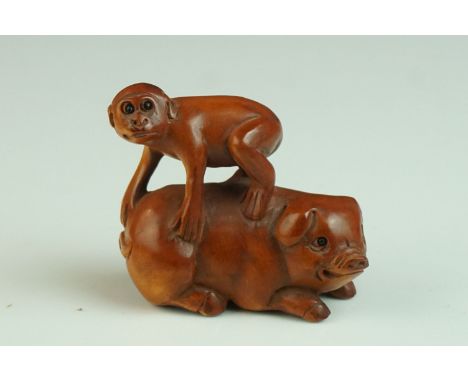 Japanese Carved Boxwood Netsuke in the form of a Monkey stood on a Pig, signed, 5cms long 