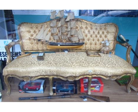 A Continental Gilt and Upholstered Settee, having a serpentine rail with shell cresting above a button upholstered back and s